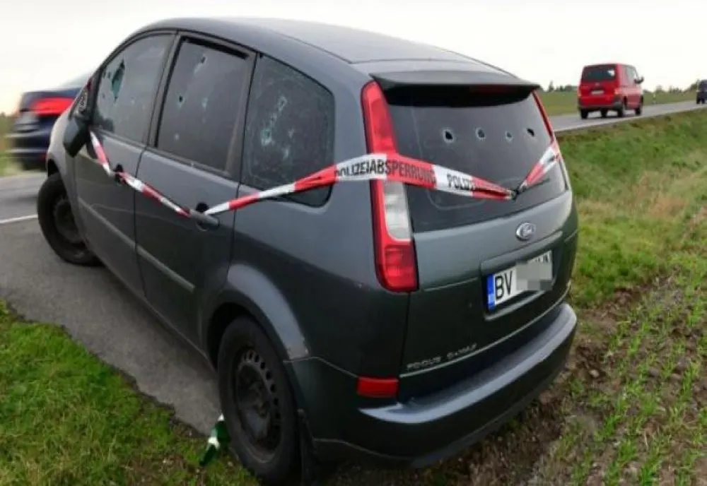Mister în Germania, în jurul unei mașini românești, cu găuri de gloațe în geamuri, abandonate de o lună la marginea unui drum